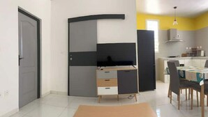 Un espace de vie compact comprenant une kitchenette, un coin repas et un bureau pliable.