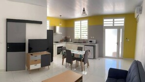 Un salon moderne avec un canapé, un téléviseur et un coin repas comprenant des chaises et une table.