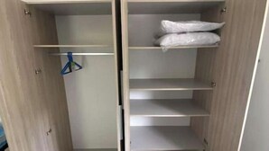 Un dressing avec de nombreuses étagères et tiroirs, une tringle à vêtements et un sol carrelé.