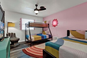 A bedroom with bunk beds, a desk, a chair, a radiator, and a ceiling fan.