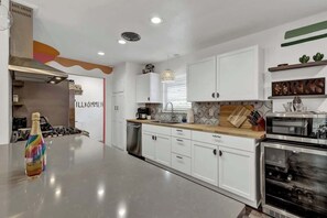 A modern kitchen with white cabinets, a wooden countertop, and stainless steel appliances.