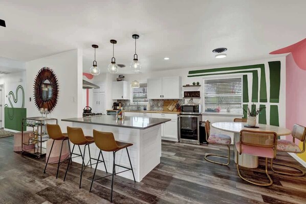 A modern kitchen with a central island, bar stools, and pendant lighting.