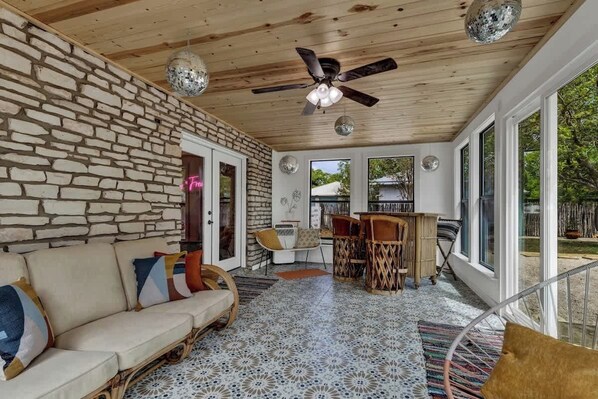 A cozy living area with a stone wall, a ceiling fan, and a dining table with chairs.