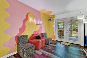 A vibrant lobby with a neon sign reading "Funky Fred," featuring a red sofa and patterned chairs.