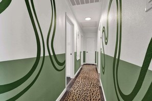 A hallway with green and white walls, patterned carpet, and a door at the end.
