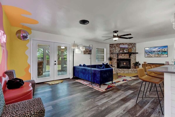 A modern living room with a blue sofa, a red chair, and a stone fireplace.
