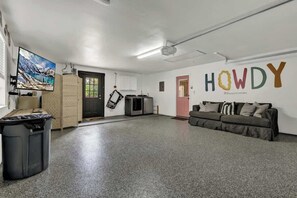 A spacious room with a large TV on the left, a sofa on the right, and a wall with the word "HOWDY".