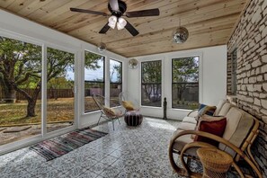 A spacious room with large windows, a ceiling fan, and a patterned floor.