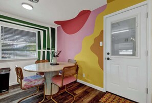 Ein Essbereich mit einem runden Tisch, Stühlen und einer Wand mit abstrakten Mustern.