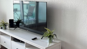 Eine weiße Unterhaltungseinrichtung mit einem Flachbildfernseher, einer Fernbedienung und einer kleinen Pflanze.