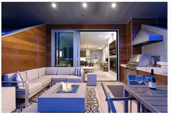 Cozy living area with fireplace, comfortable seating, and dining table for two, seamlessly connecting to the adjacent kitchen.