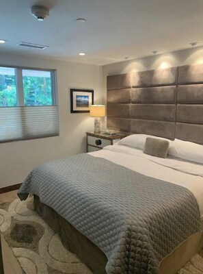 Relax in a serene bedroom with a large bed, bedside table, and framed artwork.