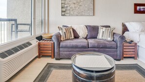 Een woonkamer met een paarse bank, een ronde salontafel, een abstract kunstwerk aan de muur en een raam met uitzicht.
