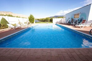 A rectangular swimming pool with clear blue water, surrounded by white lounge chairs and a brick deck. - Palisade Peach Orchard Farmhouse w/Pool & Spa 18+ (Palisade)