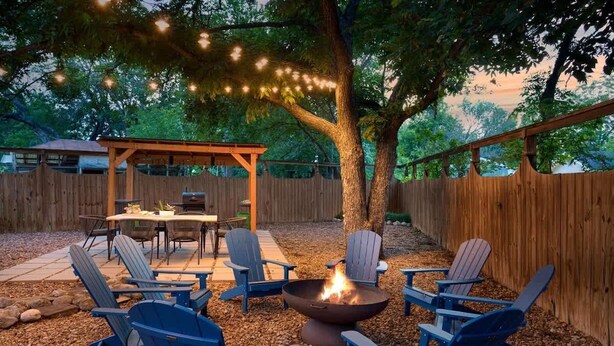 A backyard with a fire pit, outdoor seating, and string lights. - Pet-friendly, Hot tub, Close to Main St! (Fredericksburg)