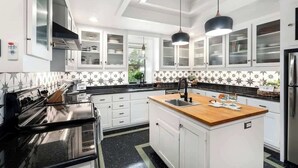 A kitchen with white cabinets, a central island, a black countertop, and a stainless steel refrigerator. - Pet-friendly, Hot tub, Close to Main St! (Fredericksburg)