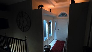 A dimly lit hallway with a clock, a red carpet, and a staircase leading to a door. - Luxury, Private,Relaxation with beautiful quiet area in the heart of the hills (Rapid City)
