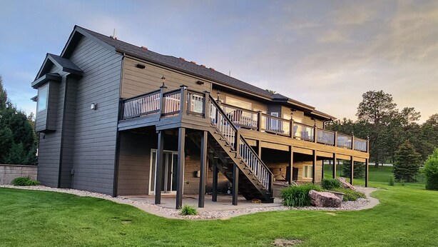 A two-story house with a covered porch and a staircase leading to the upper level. - Luxury, Private,Relaxation with beautiful quiet area in the heart of the hills (Rapid City)