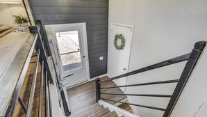 A staircase with a metal handrail, a door with a wreath, and a view of a gravel driveway.