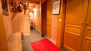 Een houten gang met een rood tapijt, houten deuren en opgehangen dierenkoppen aan de muur.