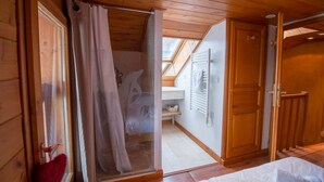 Een houten cabinestijl interieur met een douche, een bed en een dakraam.
