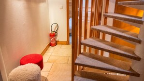 Een trap met houten treden en een leuning, leidend naar een verdieping. Een brandblusser zit aan de muur in de buurt van de trap bevestigd.
