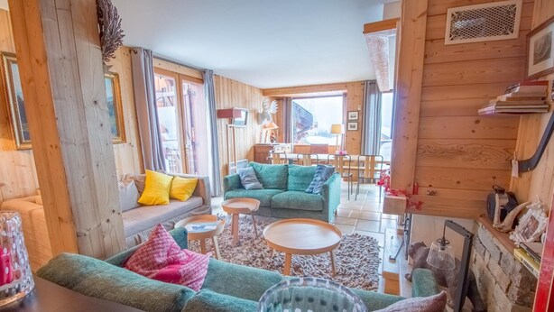 Een gezellige woonkamer met een bank, twee fauteuils, een salontafel en een open haard.
