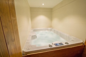 A hot tub in a room with wooden flooring and beige walls. - Chalet Clearmount hot tub and sauna in Meribel Centre (Les Allues)