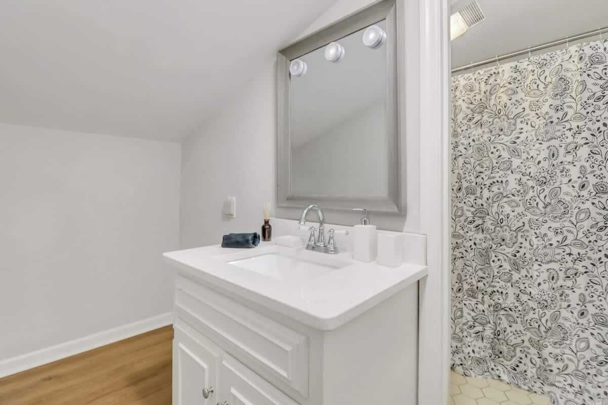 A bathroom with a white sink, mirror, and patterned shower curtain.