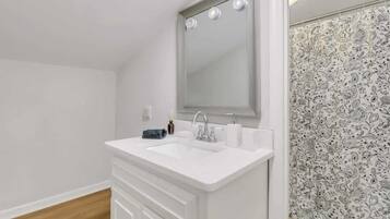 A bathroom with a white sink, mirror, and patterned shower curtain.