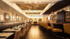 A restaurant with booths and bar seating, wooden floors, and brick walls. - Eagle Creek Loft - Close to Shops, Food, GSU! (Statesboro)