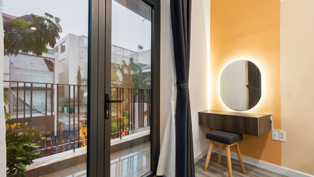 A modern bathroom with a large mirror, a wooden vanity, and a view of the street outside. - Justay Pink Church (Ho Chi Minh City)