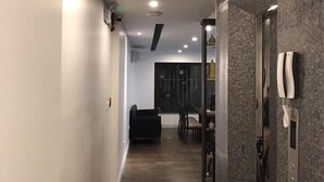 A modern hallway with a dining area in the background, featuring a dark tiled floor and a black sofa. - Justay Pink Church (Ho Chi Minh City)