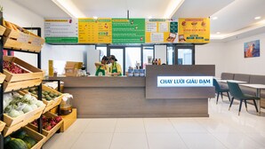 A modern cafe interior with a wooden counter, a menu board, and a seating area with tables and chairs. - Justay Pink Church (Ho Chi Minh City)