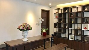 A modern interior with a wooden bench, a white vase with flowers, and a black shelving unit with various decorative items. - Justay Pink Church (Ho Chi Minh City)