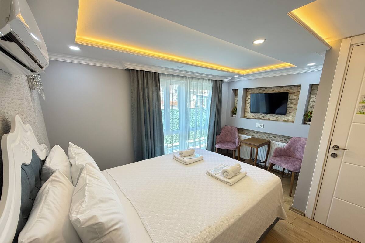 A hotel room with a bed, a TV, a desk, and a chair.