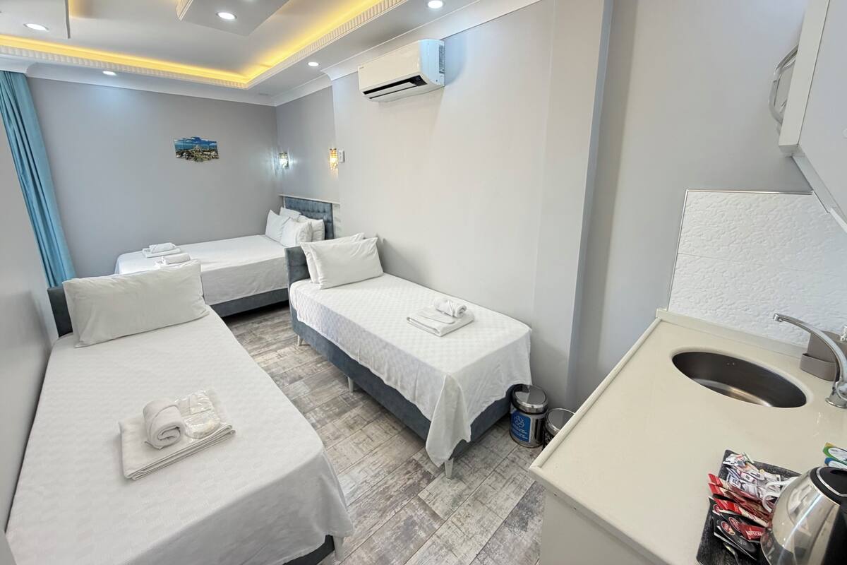 A hotel room with two single beds, a bathroom with a sink and mirror, and a small window with a view.