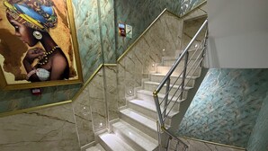 A marble staircase with a handrail, a sign indicating a terrace floor, and a partial view of a mural. - Verseca Hotel (Istanbul)
