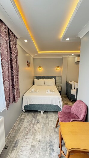 A hotel room with a bed, bedside table, chair, and a small table with a chair. - Verseca Hotel (Istanbul)