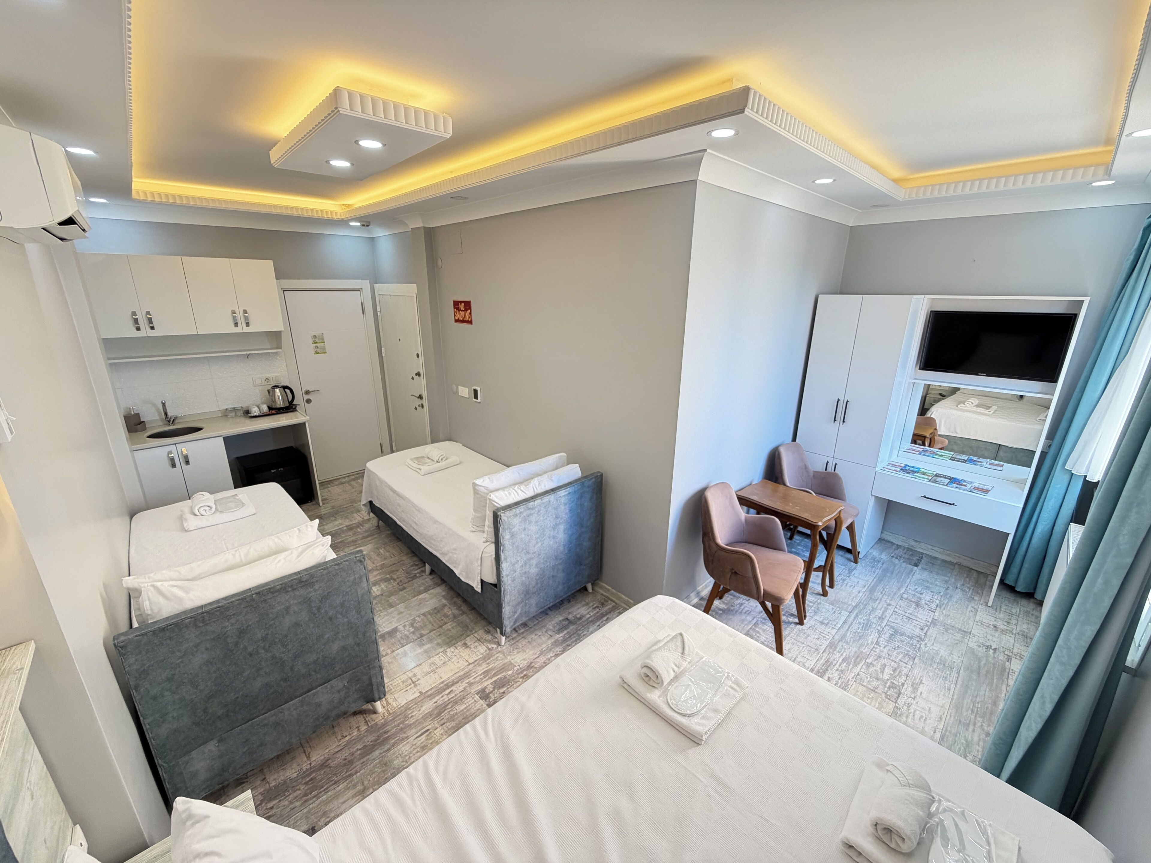Une chambre d’hôtel équipée d’une kitchenette, d’un coin repas, d’une télévision et d’un lit.