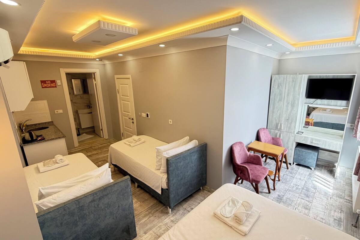 A hotel room with two beds, a desk, a chair, a TV, and a bathroom visible through an open door.