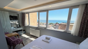 A hotel room with a bed, a desk, a chair, and a large window with a city view. - Verseca Hotel (Istanbul)