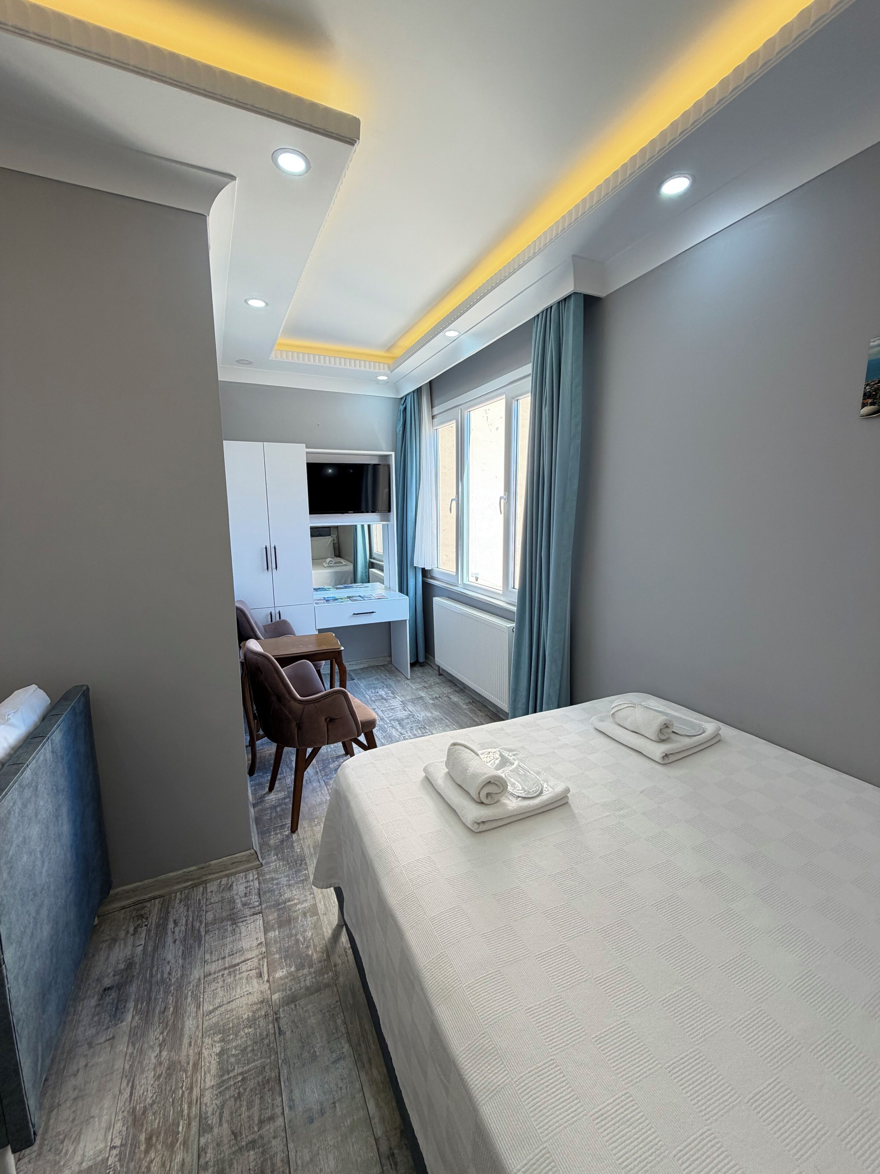 Une chambre d’hôtel équipée d’un lit, d’un bureau, d’une chaise, d’une télévision et d’une fenêtre avec des rideaux.