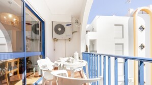 A balcony with white plastic chairs and a small round table, a Samsung air conditioning unit, and a blue railing. - Altura Inn Beach - Sol, na Praia, Varanda, Free Wifi e Ar Condicionado (Altura)
