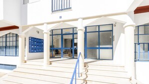 A building with a white facade, blue-framed windows, and a staircase leading to an entrance. - Altura Inn Beach - Sol, na Praia, Varanda, Free Wifi e Ar Condicionado (Altura)