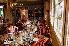 A dining area with tables set for four, surrounded by bookshelves filled with books.