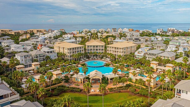 Un complex turístic amb una piscina central, diversos edificis i vista a l'oceà.