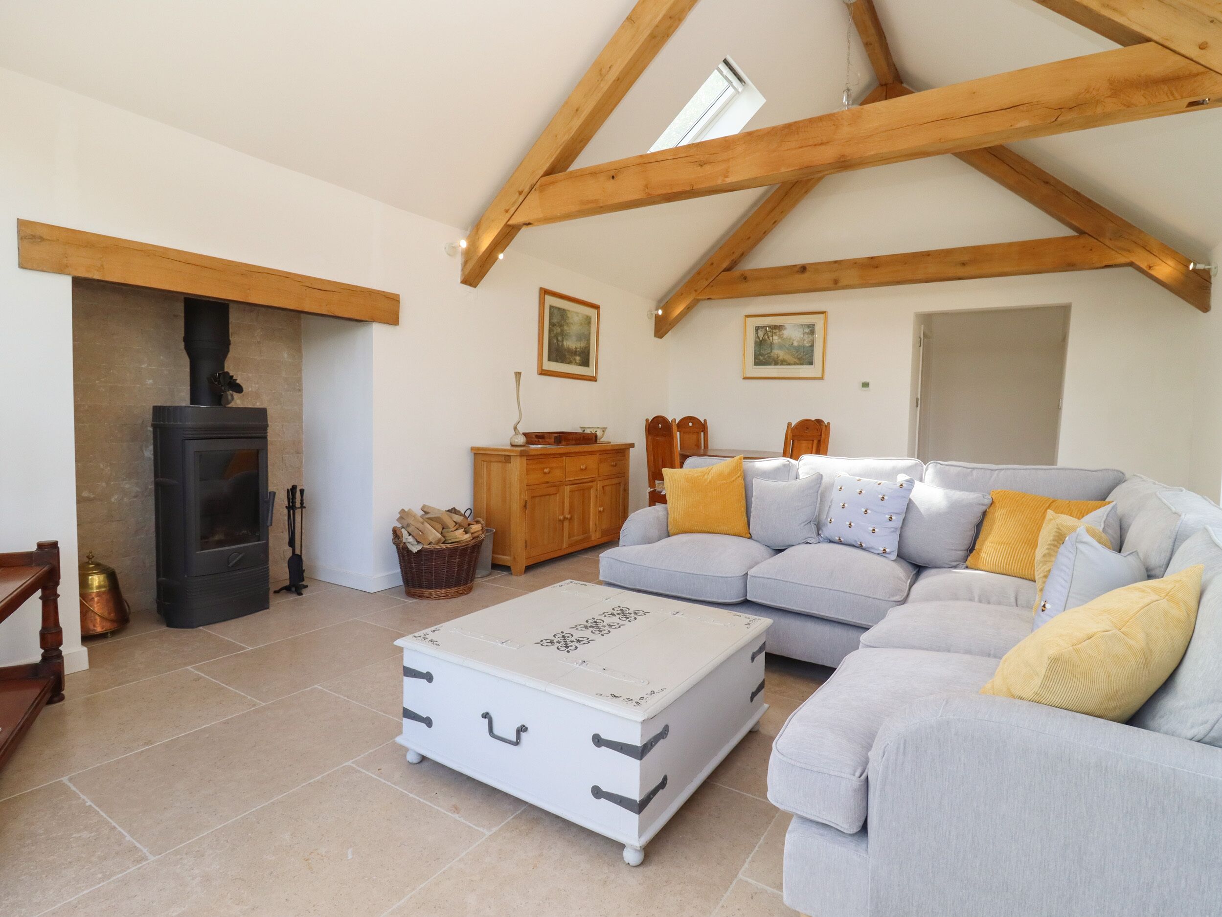 Un loft spacieux avec des poutres apparentes, une cheminée, un canapé et une commode blanche.