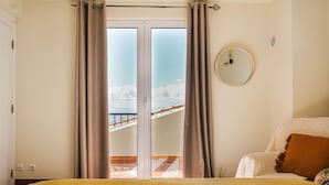A bedroom with a bed, a round mirror, and a view of a balcony with a railing. - Harmony (Air conditioning, kitchen, balcony, self-check-in, dishware and linens provided, privacy) (Ponta do Sol)