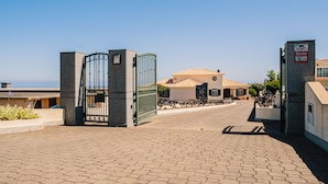 A gated entrance to a property with a paved driveway leading to a building with a tiled roof. - Harmony (Air conditioning, kitchen, balcony, self-check-in, dishware and linens provided, privacy) (Ponta do Sol)